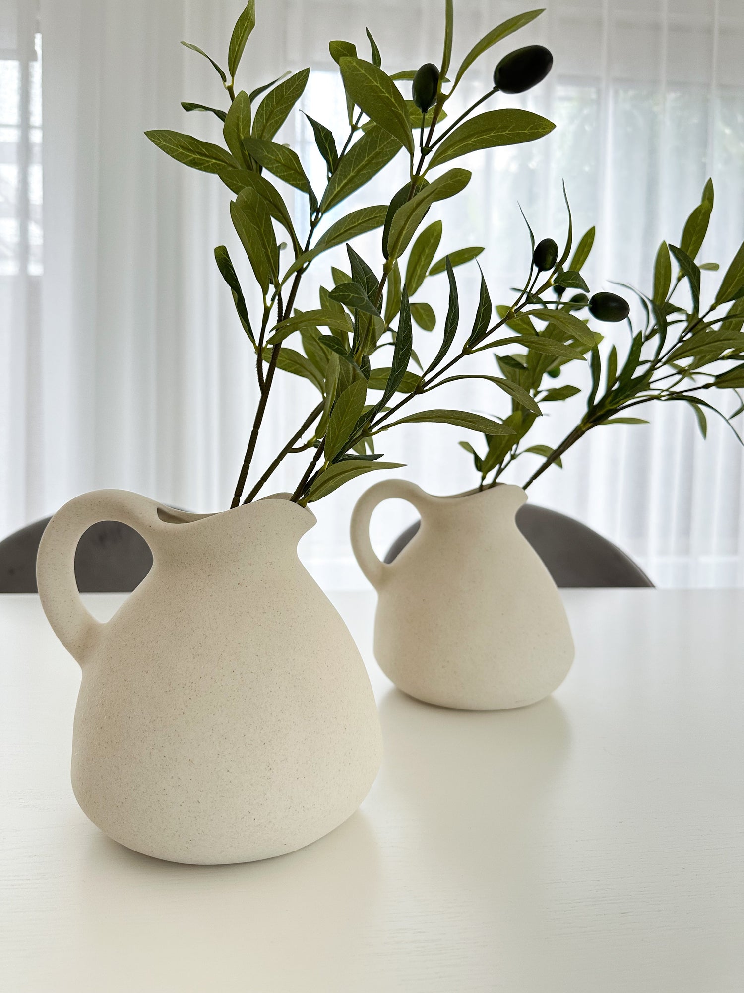 White Vase with Olive Branches standing straight on white dining table