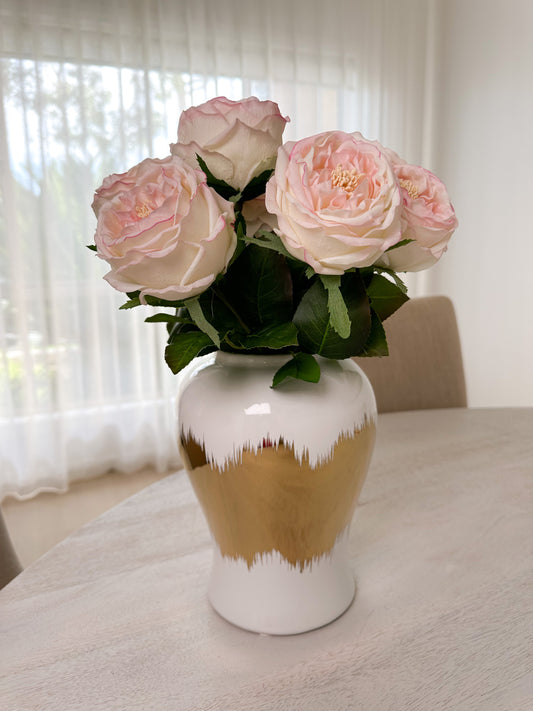 Light pink real touch peonies in white and gold small ceramic vase front view close up shot on table