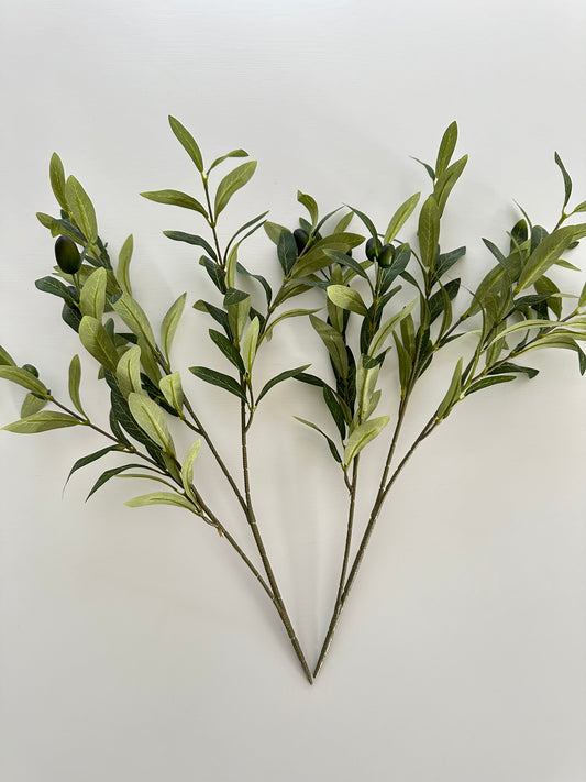 2 Olive Branches with realistic leaves and some olives laying flat on dining table